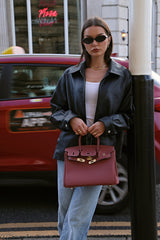 woman holding berry coloured leather handbag