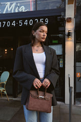 woman holding brown suede handbag